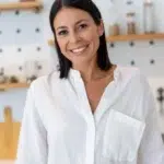 Portrait of Clara, smiling, wearing a crisp white linen blouse